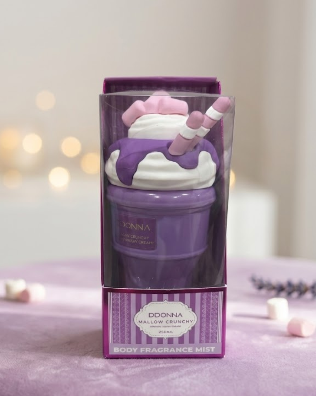 Bruma corporal Mallow Crunchy D'DONNA en empaque morado con forma de helado sobre base de terciopelo violeta