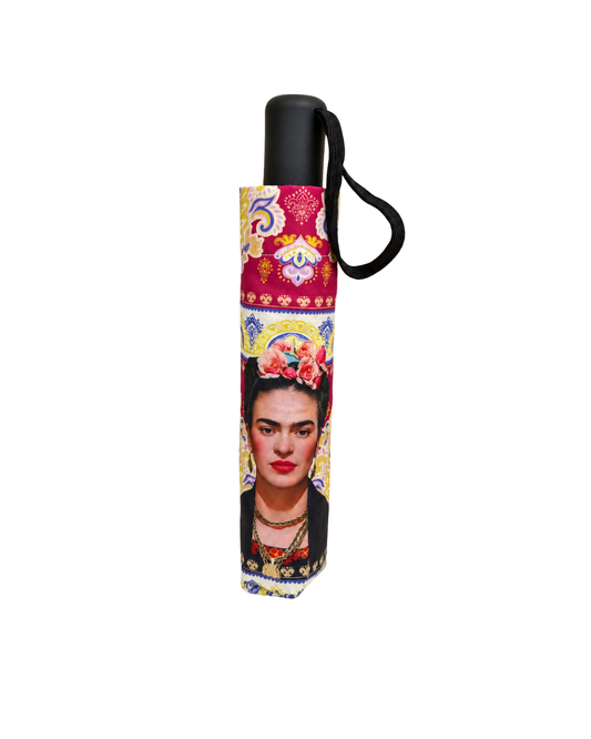 Paraguas plegable cerrado en funda con retrato de Frida Kahlo y estampado paisley granate, con mango negro y cinta de muñeca.