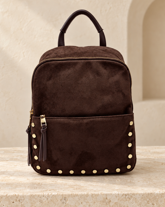Vista frontal de mochila mediana de efecto antelina marrón chocolate con bolsillo delantero y tachuelas doradas.