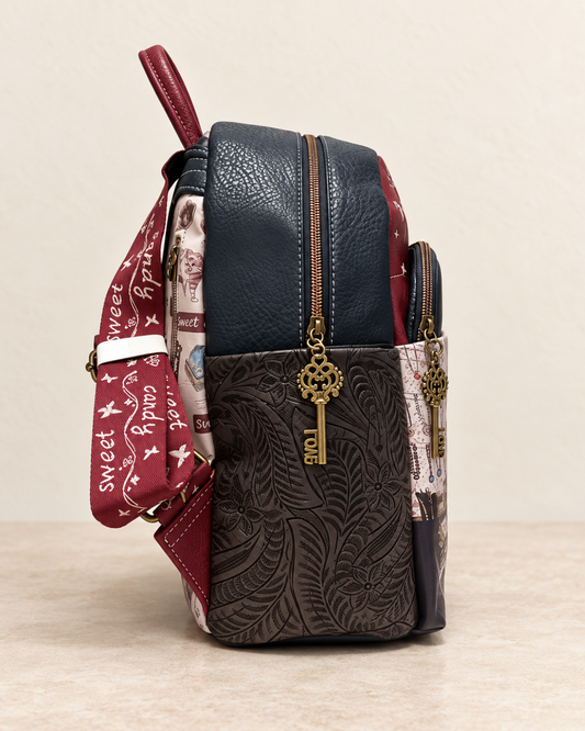 Vista lateral de mochila Sweet Candy azul marino y burdeos con hojas en relieve y tiradores metálicos con forma de llave.