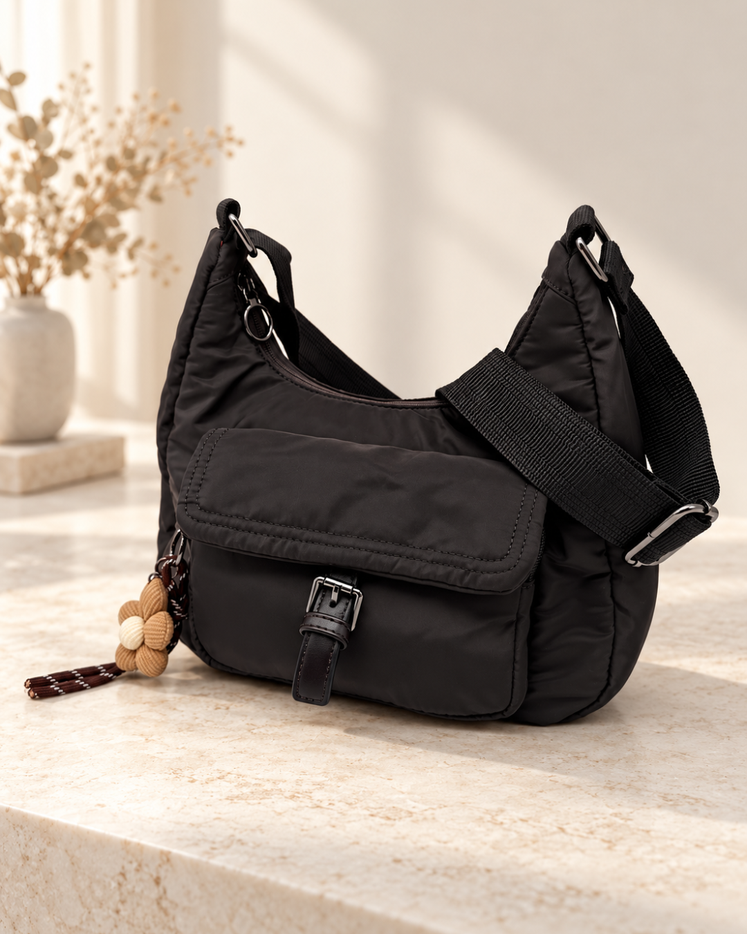 Bolso bandolera negro de nylon para mujer con bolsillo frontal, hebilla y correa ancha ajustable.