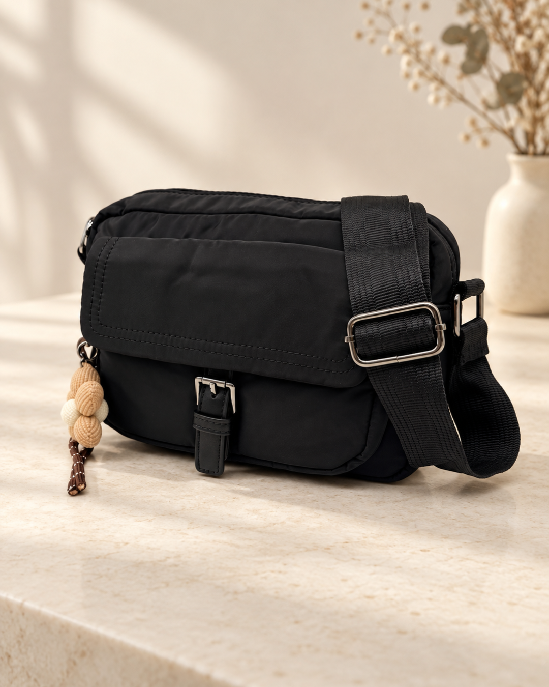Bolso bandolera negro de nylon para mujer con correa ancha ajustable y bolsillo frontal con hebilla.