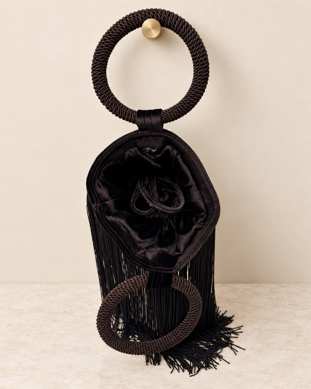 Bolso de terciopelo marrón chocolate muy oscuro con flecos abierto, mostrando el interior con cierre de cordón ajustable y sus dos asas circulares.
