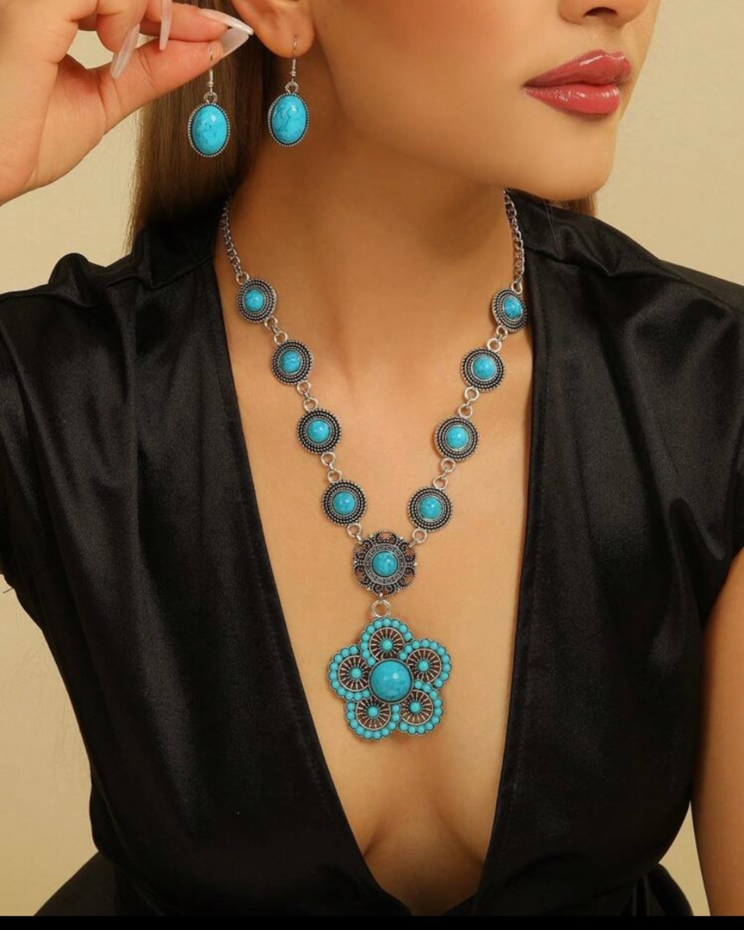 Conjunto de collar con medallón floral turquesa y pendientes a juego puesto en modelo con vestido negro.
