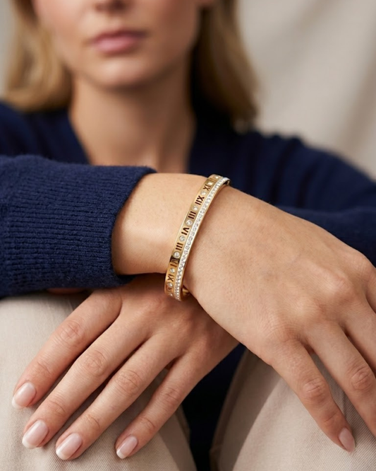 Pulsera de acero dorado con números romanos y cristales sobre soporte azul. Esto ayudará aún más a tu posicionamiento en Google Imágenes.