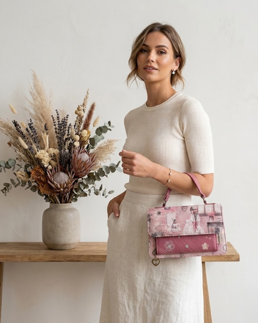 "Bolso de mano Sweet Candy color rosa con ilustración vintage de niña y perro, detalles bordados y charm de corazón sobre fondo blanco."