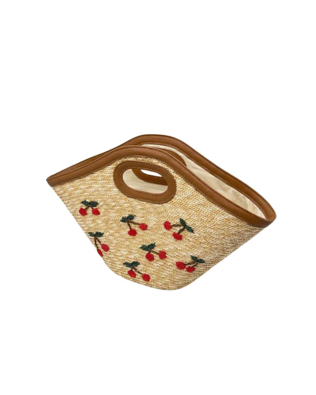 Plano frontal de bolso de rafia con forma de trapecio y cerezas rojas bordadas sobre fondo blanco.