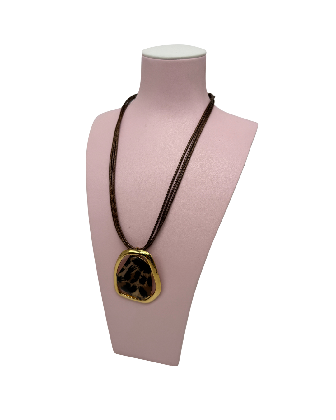 Collar de cordón marrón con un gran colgante dorado y motivo de animal print expuesto en un maniquí rosa.