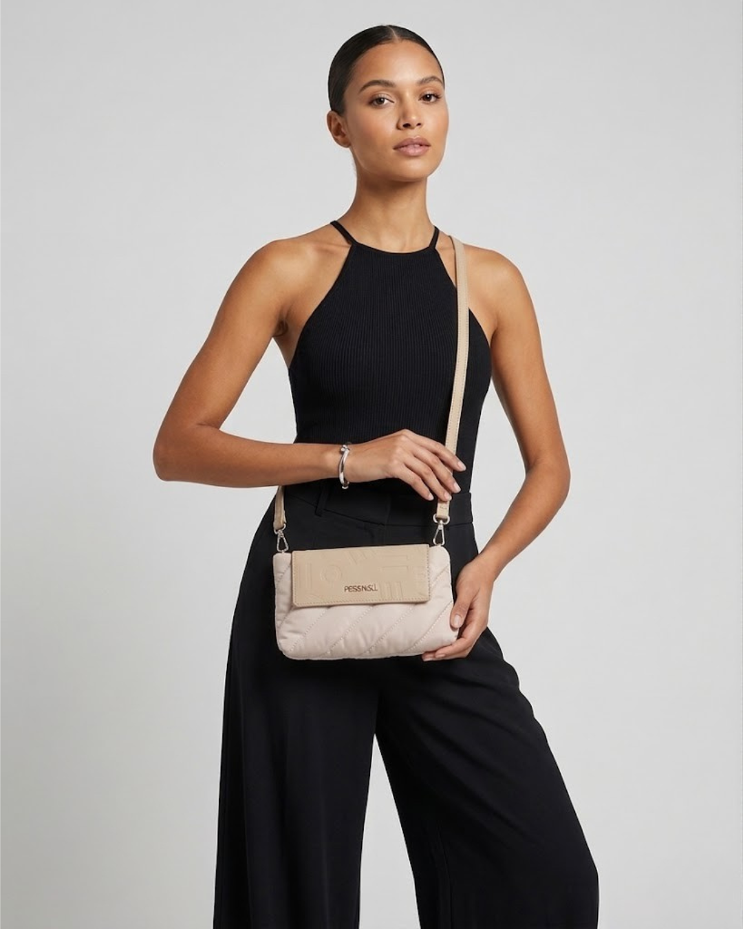 "Modelo con bolso bandolera Pepe Moll acolchado color beige, top halter negro y pantalón palazzo."
