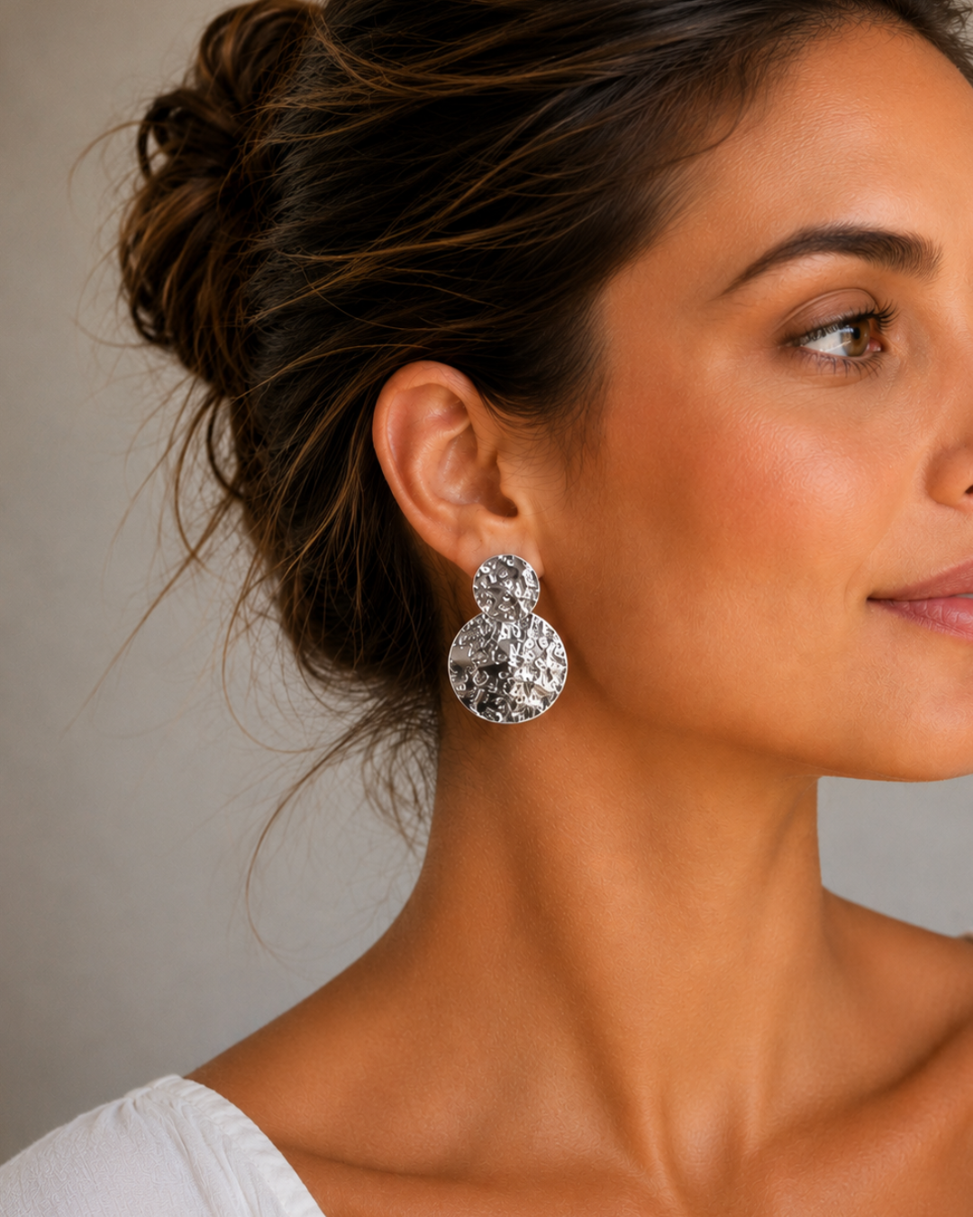 Modelo luciendo pendientes geométricos de acero plateado texturizado de Accesoriomanía con el pelo recogido informalmente.