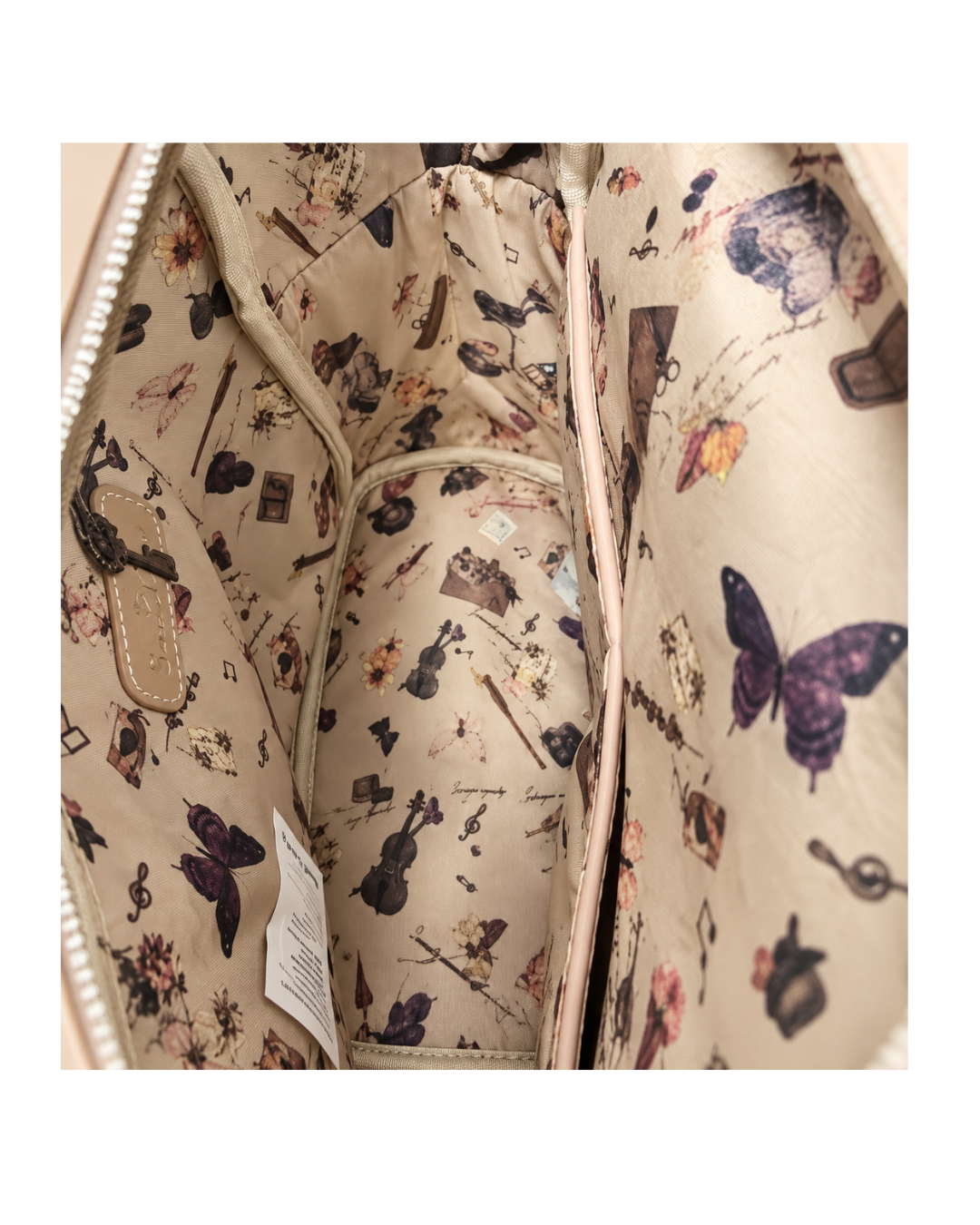 Interior de mochila Sweet Candy con forro beige estampado de mariposas y motivos musicales, y bolsillo con cremallera.