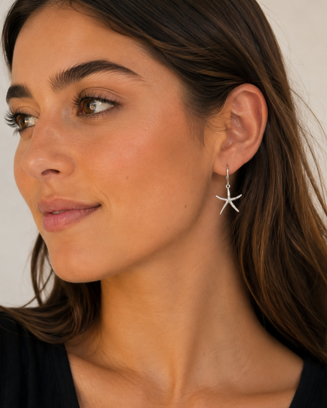 Modelo luciendo pendientes de aro con estrella de mar en tono plata de Accesoriomanía con pelo suelto.