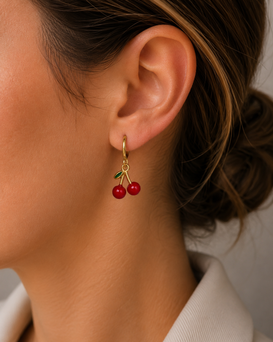 Mujer luciendo pendientes de cerezas rojas en aro de acero dorado estilo coquette