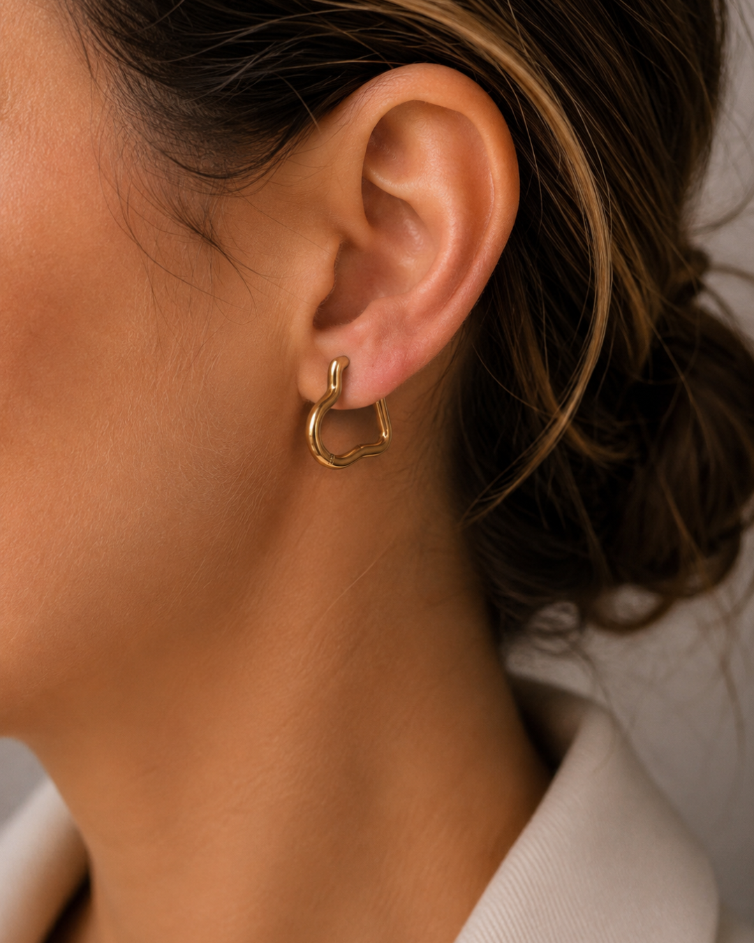 Mujer luciendo pendientes aros con forma de corazón en acero inoxidable dorado