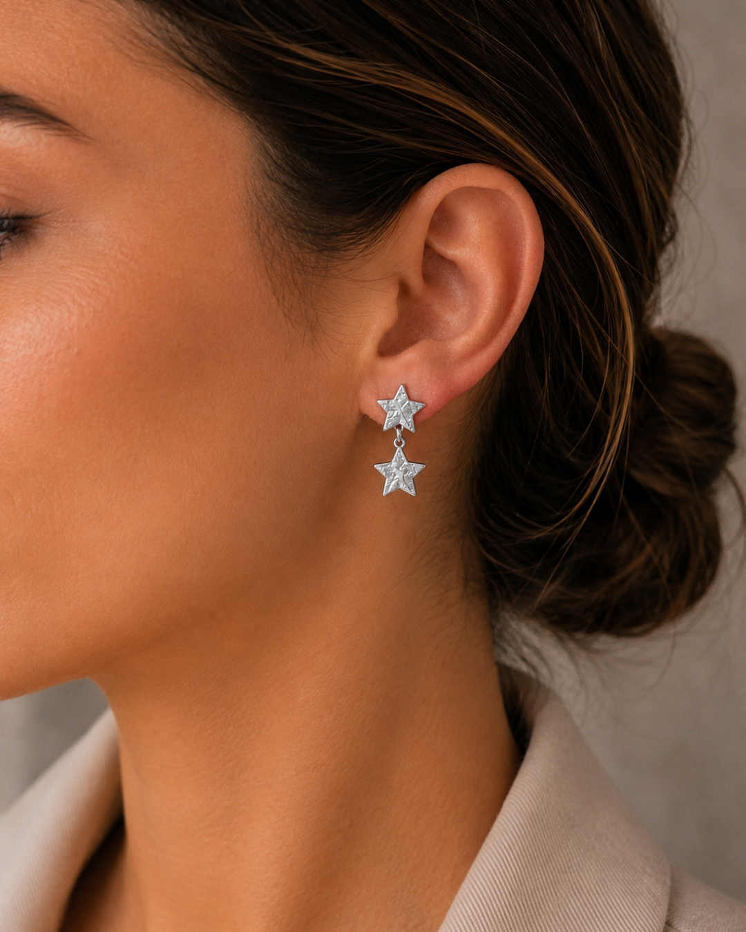 Modelo luciendo pendientes de acero plateado de doble estrella texturizada de Accesoriomanía con recogido en moño.