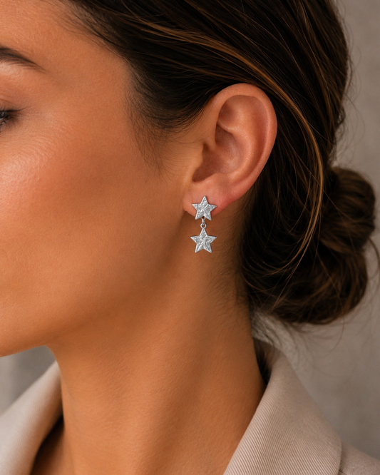 Modelo luciendo pendientes de acero plateado de doble estrella texturizada de Accesoriomanía con recogido en moño.