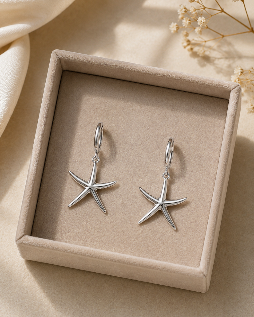 Pendientes de aro en acero inoxidable plateado con colgante de estrella de mar en estuche beige de Accesoriomanía.