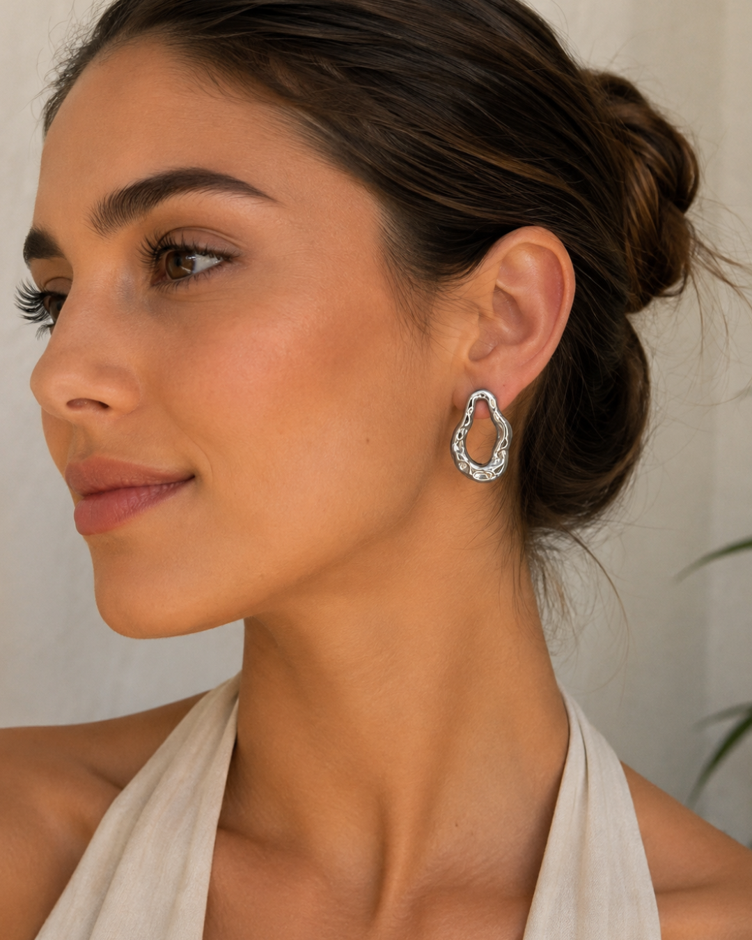 Modelo luciendo pendientes de acero plateado con forma orgánica e irregular calada de Accesoriomanía con recogido en moño.