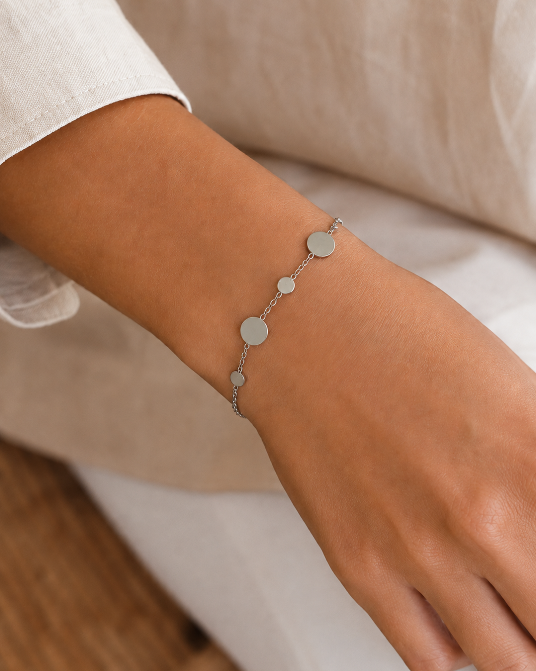 Mujer luciendo pulsera de cadena fina con círculos planos en acero inoxidable plateado