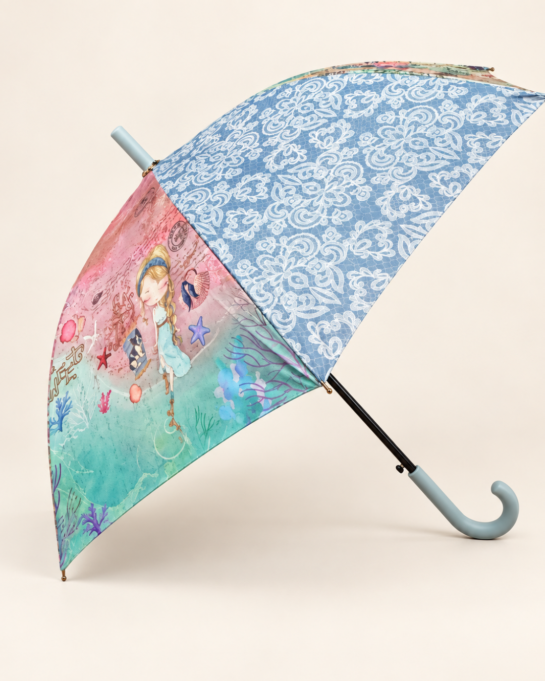 Paraguas largo abierto de perfil con ilustración de niña, motivos marinos, estampado ornamental azul y mango curvo azul claro.