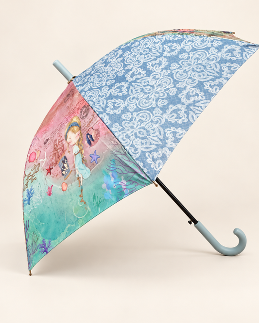 Paraguas largo abierto de perfil con ilustración de niña, motivos marinos, estampado ornamental azul y mango curvo azul claro.
