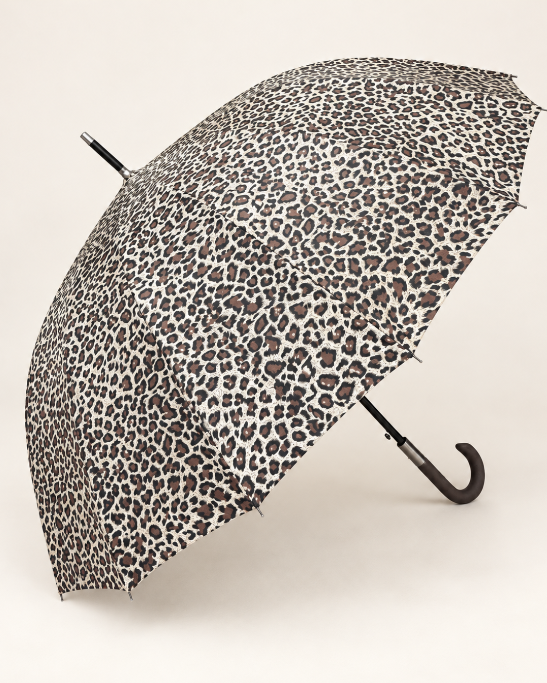 Paraguas maxi abierto con estampado animal print de leopardo y mango curvo negro sobre fondo claro.