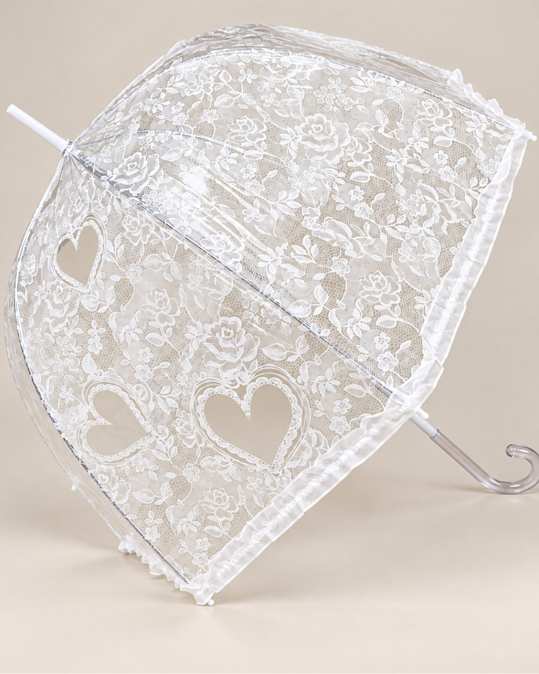 Paraguas transparente abierto de perfil con dibujo de encaje blanco, flores, corazones y mango curvo transparente.