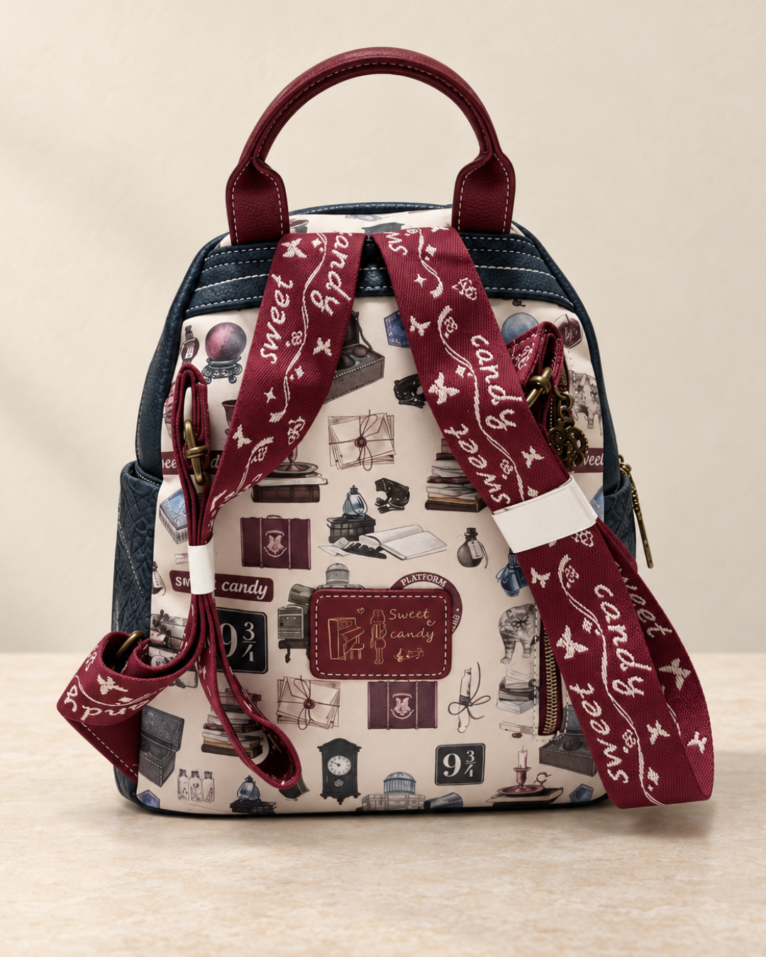 Parte trasera de mochila Sweet Candy con estampado de libros y objetos vintage, correas burdeos regulables y bolsillo con cremallera.