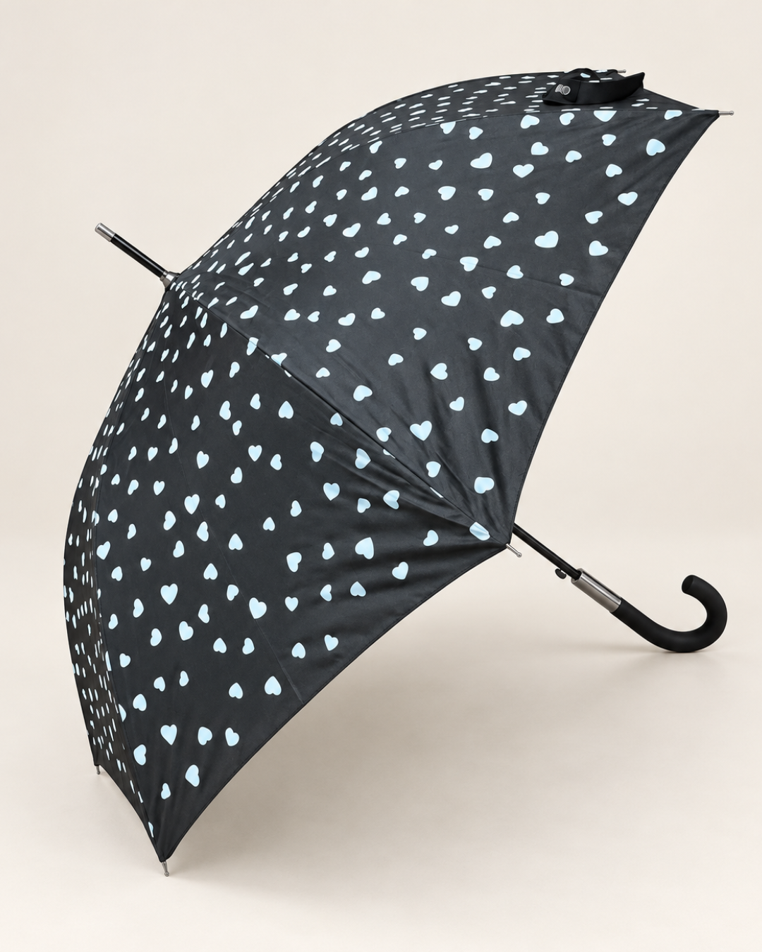 Vista de la cubierta del paraguas negro con estampado de corazones que se ponen de colores con la lluvia.