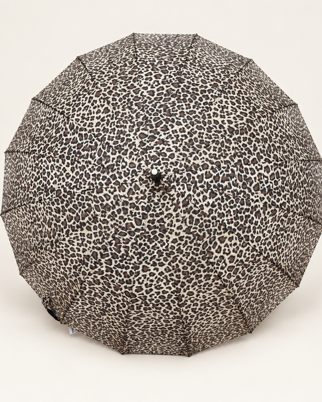 Vista exterior del paraguas extra grande abierto con estampado de leopardo en tonos beige, marrón y negro.