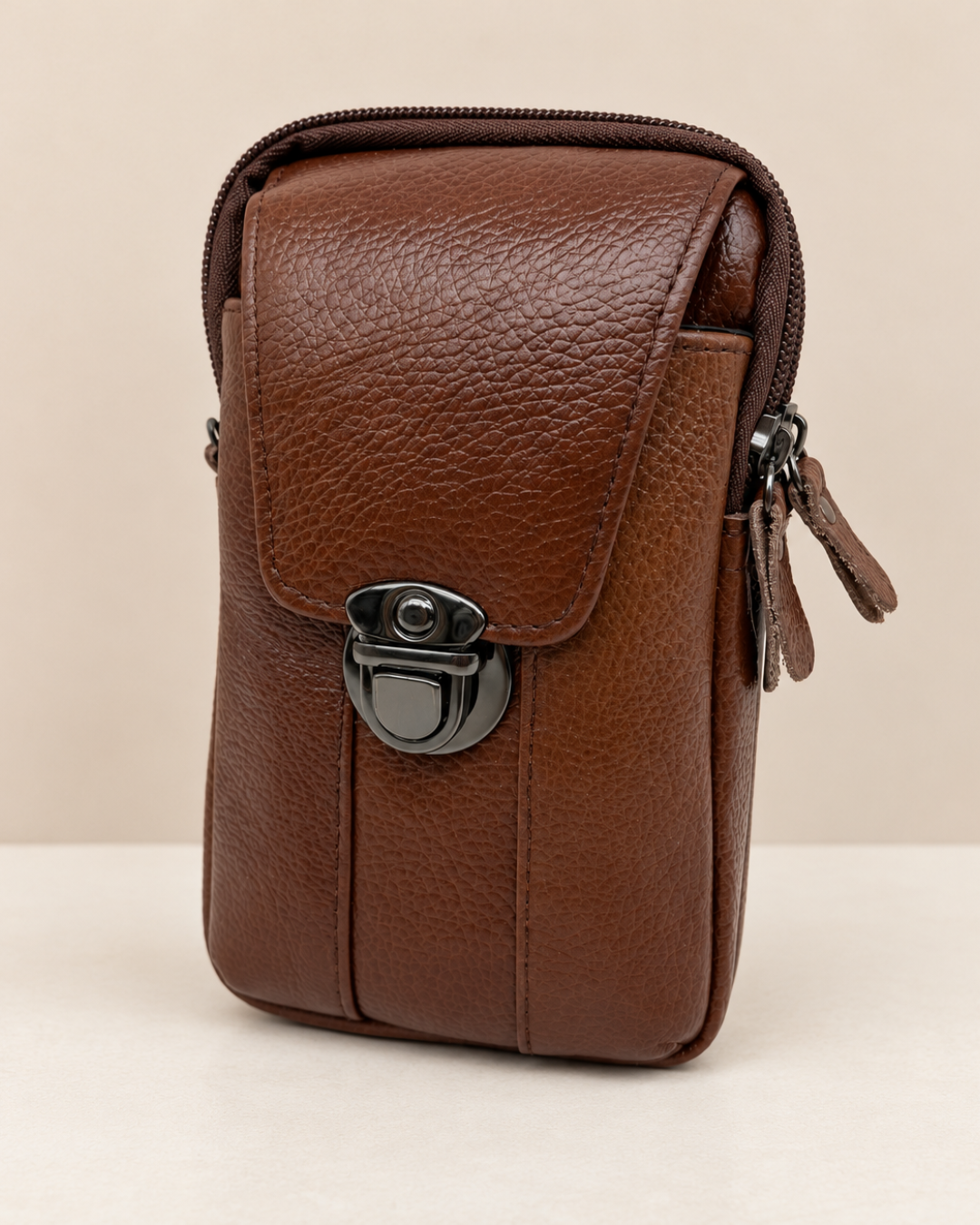 Vista frontal del bolso portamóvil marrón de hombre con textura granulada y bandolera ajustable extraíble.