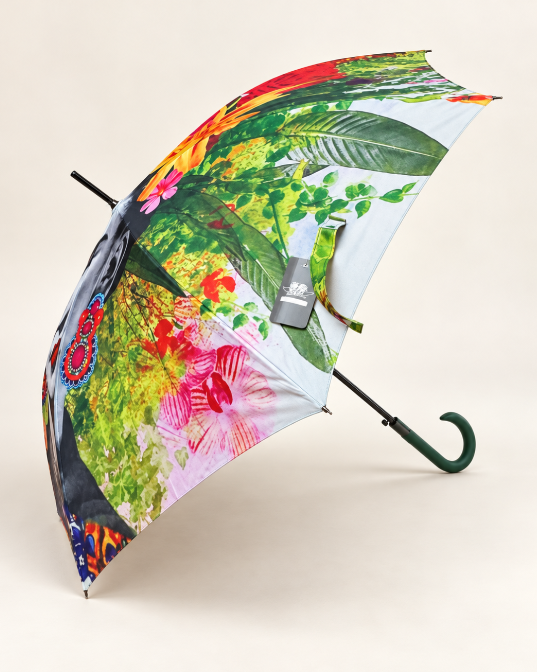 Vista lateral del paraguas largo Frida Kahlo con estampado floral multicolor, hojas verdes y mango curvo verde.