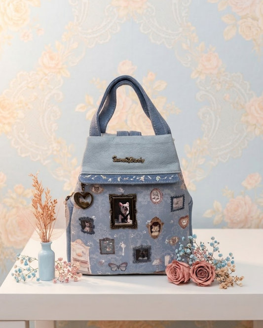 Mochila antirrobo Sweet Candy azul pastel edición limitada de perrito con bordados florales y camafeo en relieve sobre mesa decorada con flores.